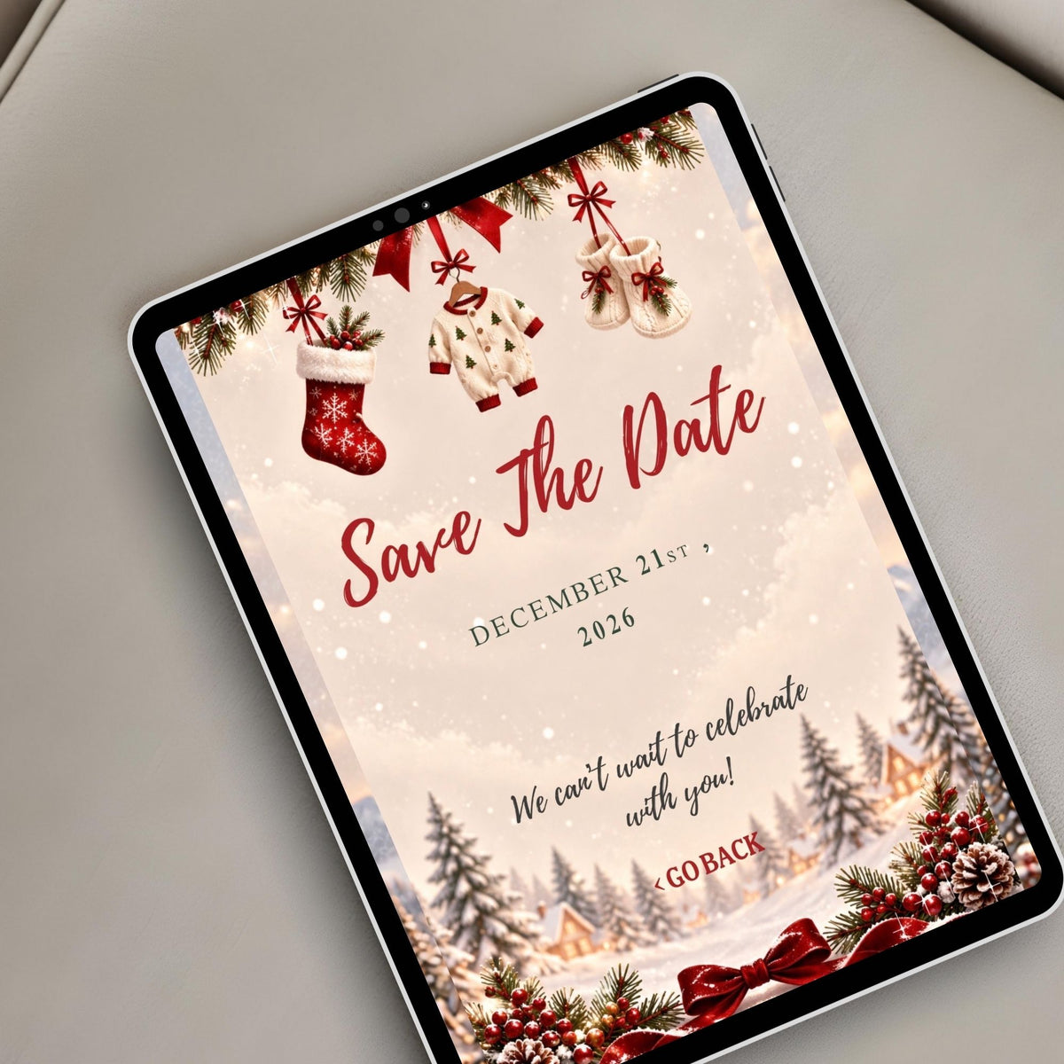 Festive Christmas village baby shower Save the Date website displayed on a tablet with winter illustrations and burgundy ribbon decorations.
